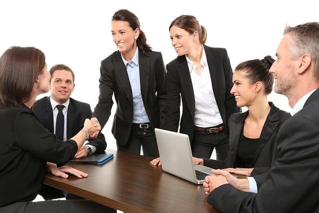 Business team meeting with a handshake over a laptop — secure collaboration and compliance